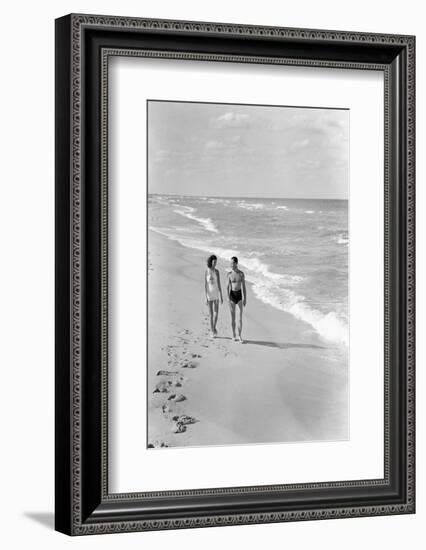 1930s 1940s COUPLE WEARING BATHING SUITS WALKING TALKING TOGETHER ON BRIGHT WARM SUNLIT SEASHORE...-H. Armstrong Roberts-Framed Photographic Print