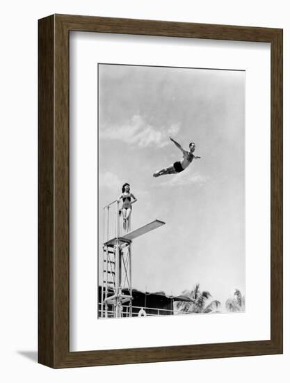 1930s 1940s SHAPELY WOMAN WATCHING MAN SWAN DIVE OFF HIGH DIVING BOARD-H. Armstrong Roberts-Framed Photographic Print