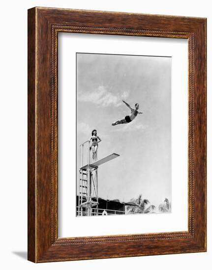 1930s 1940s SHAPELY WOMAN WATCHING MAN SWAN DIVE OFF HIGH DIVING BOARD-H. Armstrong Roberts-Framed Photographic Print