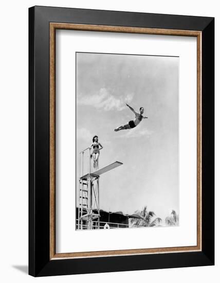 1930s 1940s SHAPELY WOMAN WATCHING MAN SWAN DIVE OFF HIGH DIVING BOARD-H. Armstrong Roberts-Framed Photographic Print