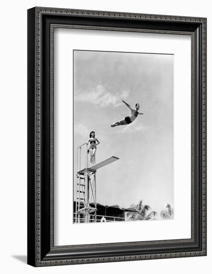 1930s 1940s SHAPELY WOMAN WATCHING MAN SWAN DIVE OFF HIGH DIVING BOARD-H. Armstrong Roberts-Framed Photographic Print