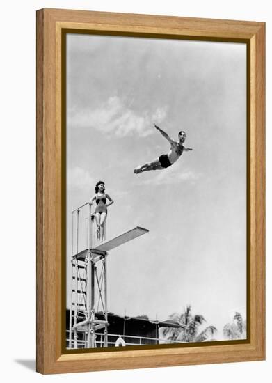 1930s 1940s SHAPELY WOMAN WATCHING MAN SWAN DIVE OFF HIGH DIVING BOARD-H. Armstrong Roberts-Framed Premier Image Canvas