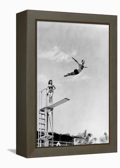 1930s 1940s SHAPELY WOMAN WATCHING MAN SWAN DIVE OFF HIGH DIVING BOARD-H. Armstrong Roberts-Framed Premier Image Canvas