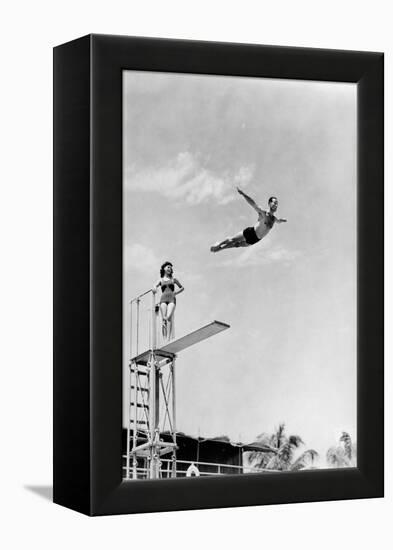 1930s 1940s SHAPELY WOMAN WATCHING MAN SWAN DIVE OFF HIGH DIVING BOARD-H. Armstrong Roberts-Framed Premier Image Canvas