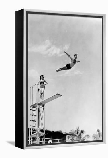 1930s 1940s SHAPELY WOMAN WATCHING MAN SWAN DIVE OFF HIGH DIVING BOARD-H. Armstrong Roberts-Framed Premier Image Canvas