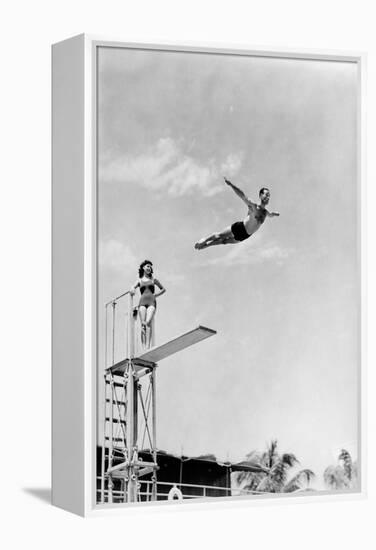 1930s 1940s SHAPELY WOMAN WATCHING MAN SWAN DIVE OFF HIGH DIVING BOARD-H. Armstrong Roberts-Framed Premier Image Canvas