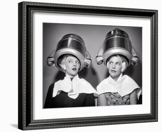 1950s TWO WOMEN SITTING UNDER BEAUTY SALON HAIR DRYERS WEARING HAIRNETS TOWELS TALKING GOSSIP-Panoramic Images-Framed Photographic Print