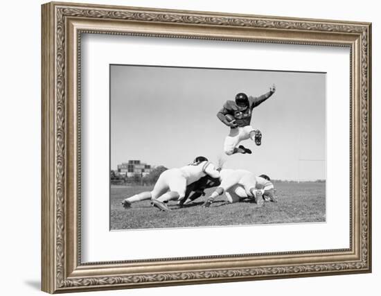 1960s FOOTBALL PLAYER JUMPING OVER BLOCKED PLAYERS-H. Armstrong Roberts-Framed Photographic Print