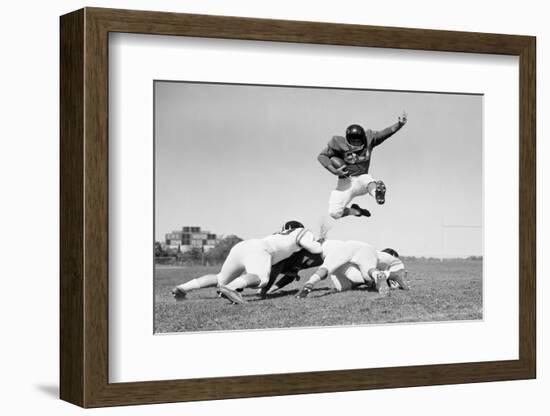 1960s FOOTBALL PLAYER JUMPING OVER BLOCKED PLAYERS-H. Armstrong Roberts-Framed Photographic Print