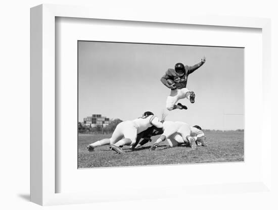 1960s FOOTBALL PLAYER JUMPING OVER BLOCKED PLAYERS-H. Armstrong Roberts-Framed Photographic Print