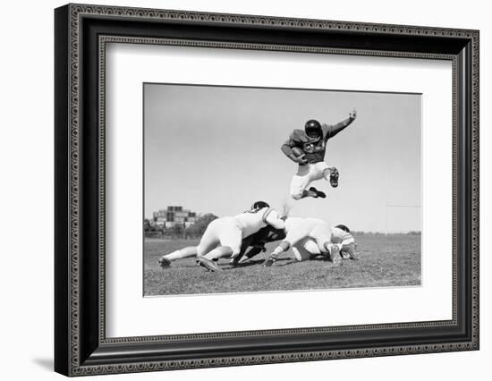 1960s FOOTBALL PLAYER JUMPING OVER BLOCKED PLAYERS-H. Armstrong Roberts-Framed Photographic Print