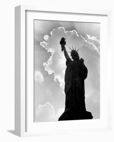 1960s Silhouette of Statue of Liberty with Sun Ray Clouds Behind-null-Framed Photographic Print