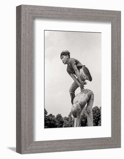 1970s TWO BOYS PLAYING LEAPFROG ONE VAULTING OVER THE OTHER-H. Armstrong Roberts-Framed Photographic Print