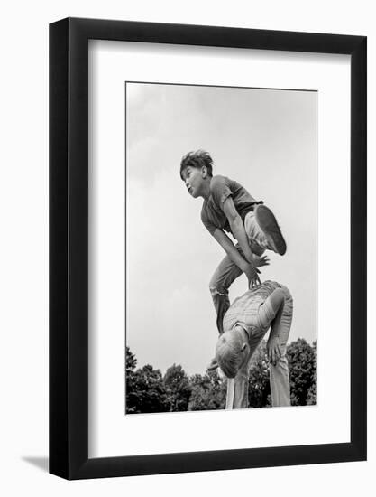 1970s TWO BOYS PLAYING LEAPFROG ONE VAULTING OVER THE OTHER-H. Armstrong Roberts-Framed Photographic Print