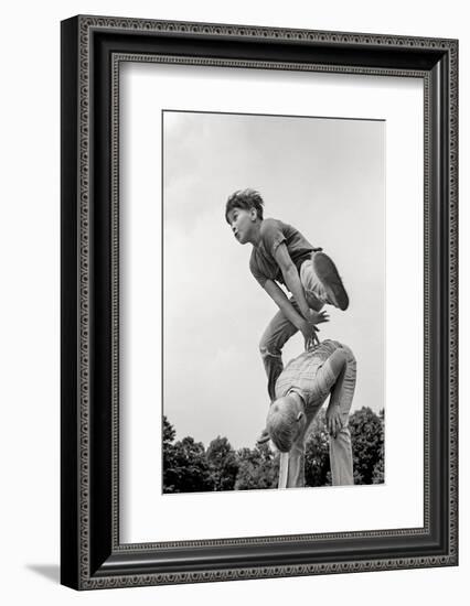 1970s TWO BOYS PLAYING LEAPFROG ONE VAULTING OVER THE OTHER-H. Armstrong Roberts-Framed Photographic Print