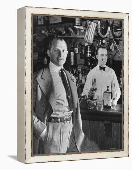 21 Club's Jack Kriendler Relaxing at Bar with Drink, Bartender Holding Bottle on Other Side of Bar-Eric Schaal-Framed Premier Image Canvas