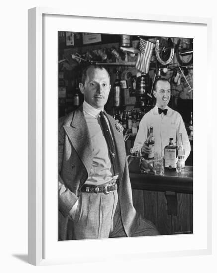 21 Club's Jack Kriendler Relaxing at Bar with Drink, Bartender Holding Bottle on Other Side of Bar-Eric Schaal-Framed Premium Photographic Print