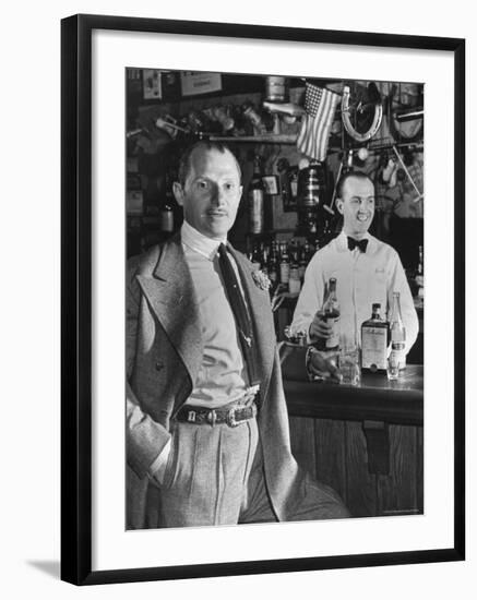 21 Club's Jack Kriendler Relaxing at Bar with Drink, Bartender Holding Bottle on Other Side of Bar-Eric Schaal-Framed Premium Photographic Print