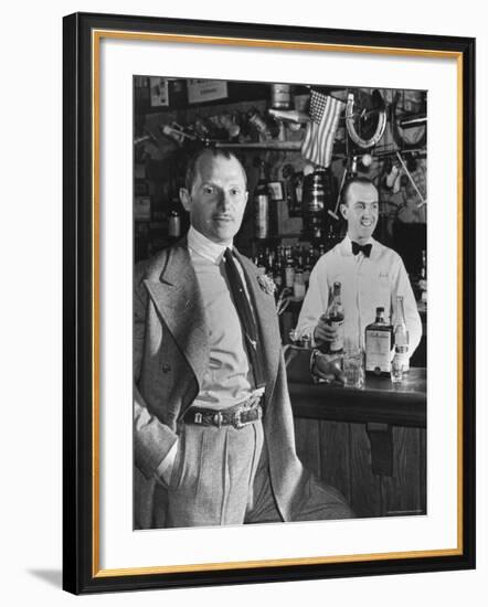 21 Club's Jack Kriendler Relaxing at Bar with Drink, Bartender Holding Bottle on Other Side of Bar-Eric Schaal-Framed Premium Photographic Print