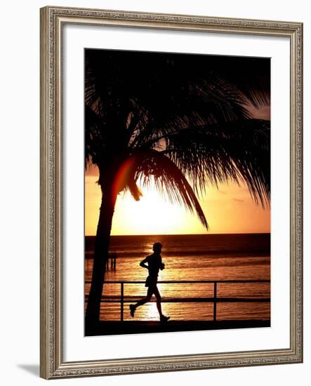 A Afternoon Runner Passes Under a Palm Tree as the Sun Sets Behind-null-Framed Photographic Print