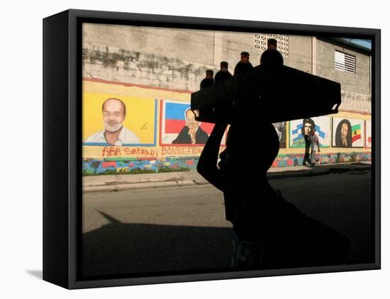 A Boy Carrying Bottles on His Head Passes by a Wall with Pictures of Haitian President Renel Preval-Ariana Cubillos-Framed Premier Image Canvas