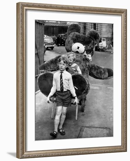 A Boy Gives a Ride to a Little Girl and a 9-Foot Teddy Bear at the Opening of the British Toy Fair-null-Framed Photographic Print