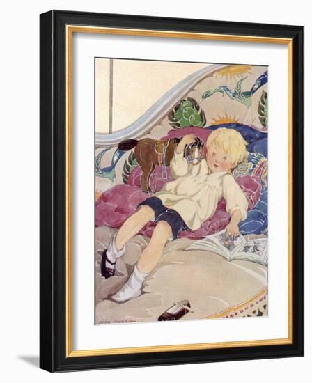 A Boy Lying on a Bed with a Book and a Toy Horse-Anne Anderson-Framed Art Print