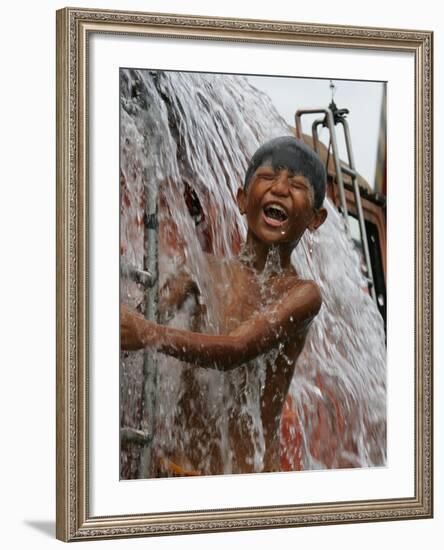 A Boy Takes Advantage of an Overflowing Firetruck Which was Used to Put out a Fire-null-Framed Photographic Print