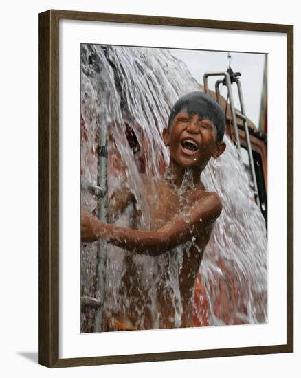 A Boy Takes Advantage of an Overflowing Firetruck Which was Used to Put out a Fire-null-Framed Photographic Print