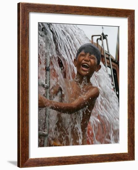 A Boy Takes Advantage of an Overflowing Firetruck Which was Used to Put out a Fire-null-Framed Photographic Print