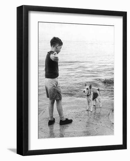 A Boy Throws Stones into the Sea for His Dog to Retrieve: the Dog Looks Up Expectantly-Henry Grant-Framed Photographic Print