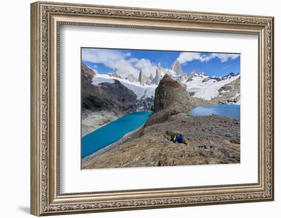 A couple in mountain gear rests on rocks with view to Lago de los Tres and Mount Fitz Roy, Patagoni-Fernando Carniel Machado-Framed Photographic Print