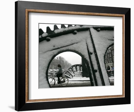 A Cyclist Passes a Draw Bridge as Snow Covers the City Center of Amsterdam-null-Framed Photographic Print