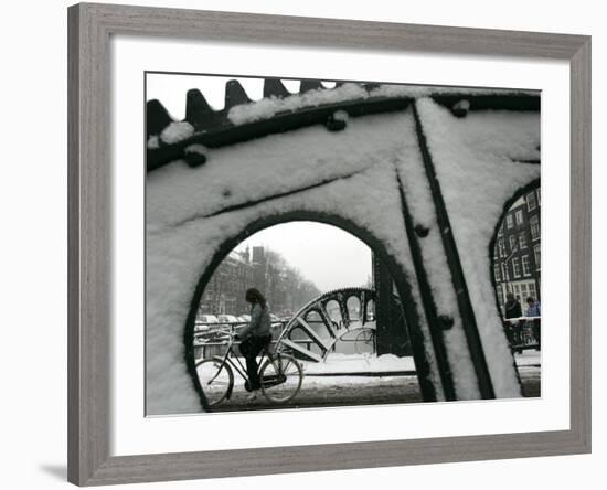 A Cyclist Passes a Draw Bridge as Snow Covers the City Center of Amsterdam-null-Framed Photographic Print