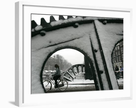 A Cyclist Passes a Draw Bridge as Snow Covers the City Center of Amsterdam-null-Framed Photographic Print