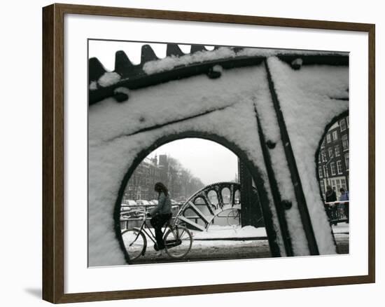 A Cyclist Passes a Draw Bridge as Snow Covers the City Center of Amsterdam-null-Framed Photographic Print