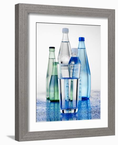 A Glass in Front of Mineral Water Bottles-Alexander Feig-Framed Photographic Print