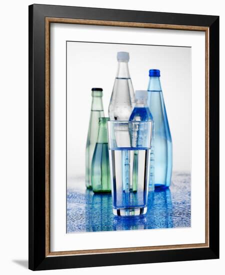 A Glass in Front of Mineral Water Bottles-Alexander Feig-Framed Photographic Print