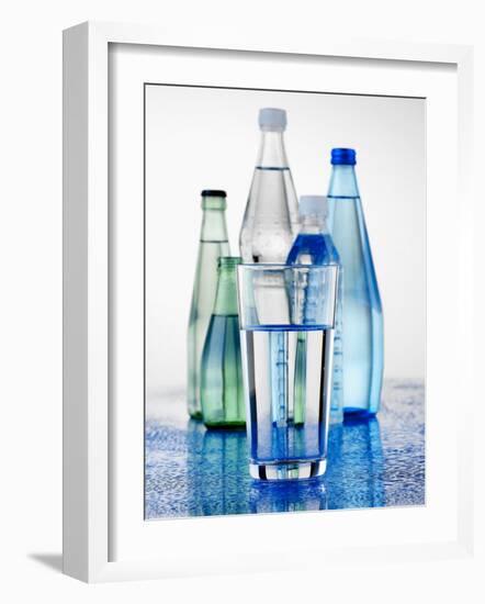 A Glass in Front of Mineral Water Bottles-Alexander Feig-Framed Photographic Print