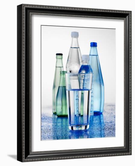 A Glass in Front of Mineral Water Bottles-Alexander Feig-Framed Photographic Print