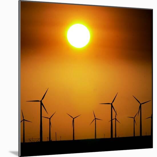 A Group of Wind Turbines are Silhouetted by the Setting Sun-Charlie Riedel-Mounted Photographic Print