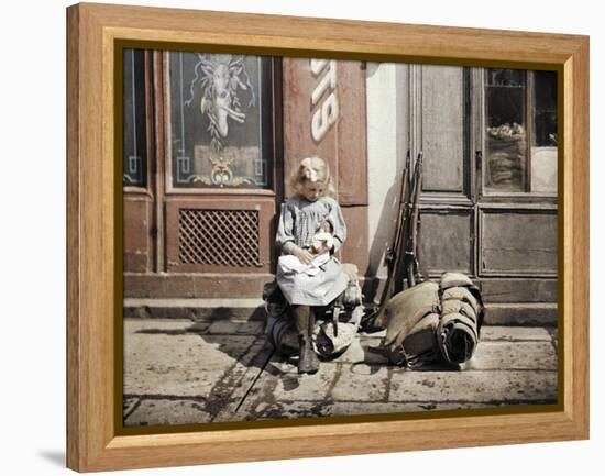 A Little Girl Playing with Her Doll; Two Guns and a Knapsack are Next to He-Fernand Cuville-Framed Premier Image Canvas