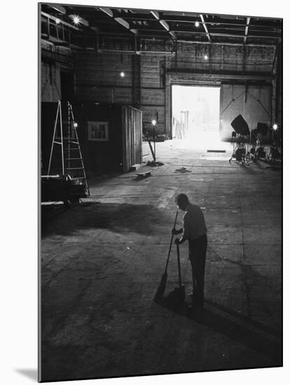 A Man Cleaning Up the Empty Sound Stage-null-Mounted Photographic Print