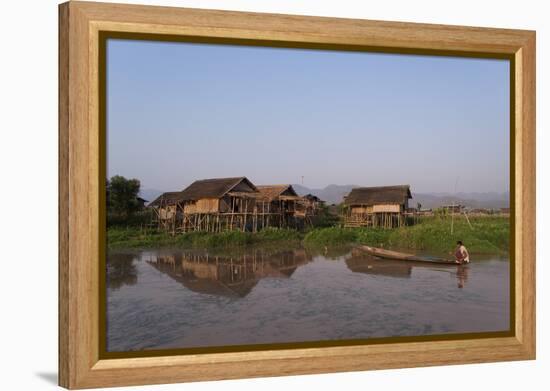 A man paddles his canoe past one of the floating villages on Inle Lake, Myanmar (Burma), Asia-Alex Treadway-Framed Premier Image Canvas