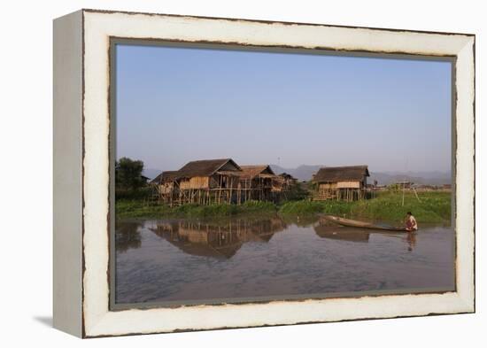 A man paddles his canoe past one of the floating villages on Inle Lake, Myanmar (Burma), Asia-Alex Treadway-Framed Premier Image Canvas