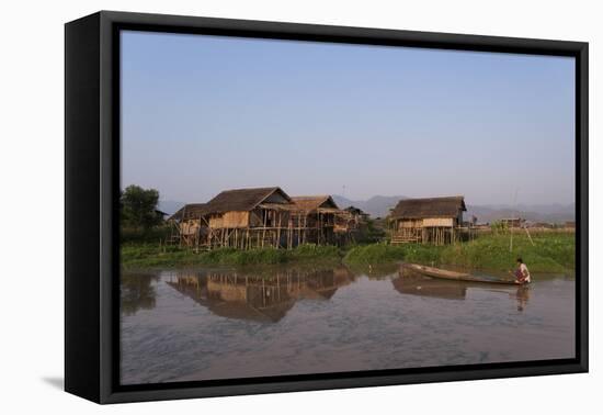 A man paddles his canoe past one of the floating villages on Inle Lake, Myanmar (Burma), Asia-Alex Treadway-Framed Premier Image Canvas