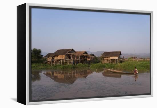 A man paddles his canoe past one of the floating villages on Inle Lake, Myanmar (Burma), Asia-Alex Treadway-Framed Premier Image Canvas