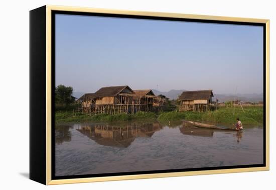 A man paddles his canoe past one of the floating villages on Inle Lake, Myanmar (Burma), Asia-Alex Treadway-Framed Premier Image Canvas