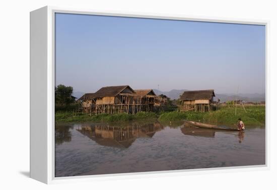 A man paddles his canoe past one of the floating villages on Inle Lake, Myanmar (Burma), Asia-Alex Treadway-Framed Premier Image Canvas