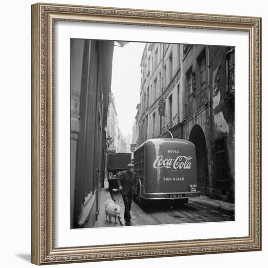 A Man Walks His Dog Beside a Bus with Coca Cola Advertisement, France, 1950-Mark Kauffman-Framed Photographic Print